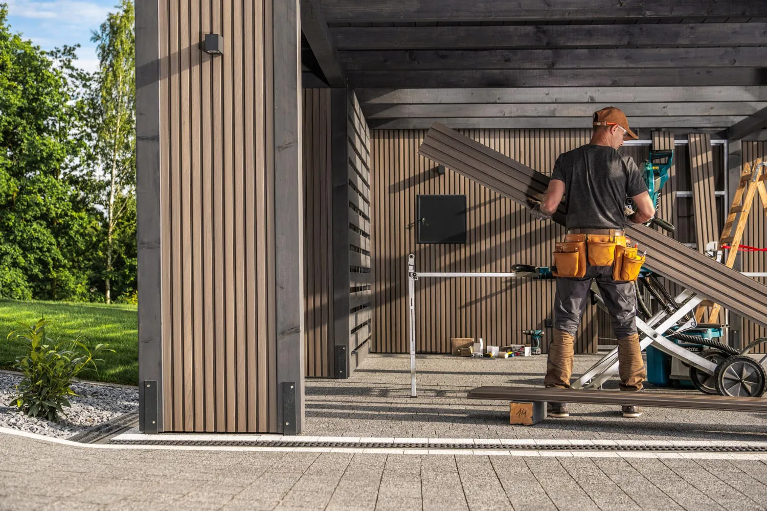 Polnischer Handwerker bei der Montage eines modernen Carports mit Holzverkleidung